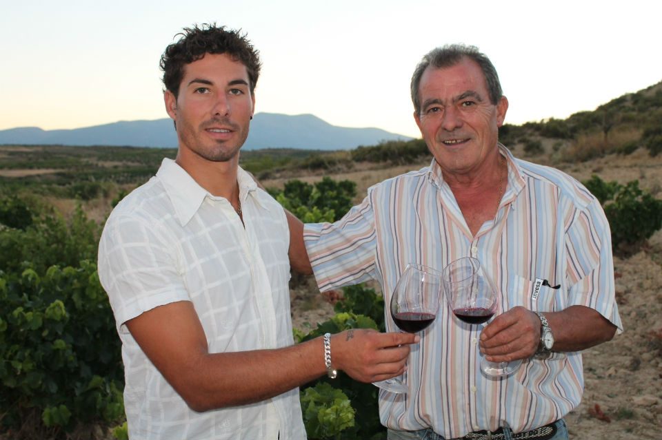 Brindis con vino tinto entre las viñas, con la sierra al fondo